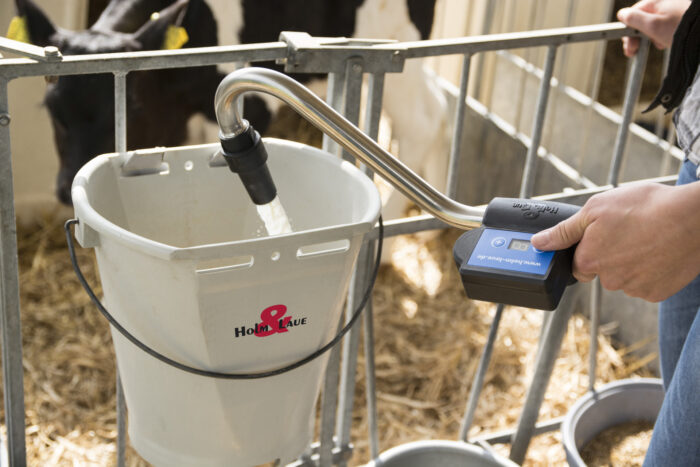 Este primer plano muestra la dosificación de la leche en un cubo con tetina con la ayuda del control remoto.