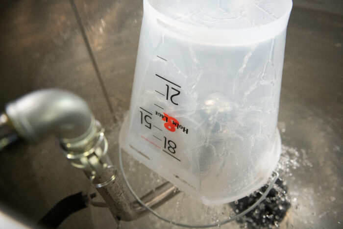 På dette billede ses FlushMaster sprøjtehovedet, som rengør en sutspand, der holdes ovenover.